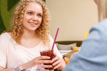 Obraz na płótnie Canvas Smiling girl holding cocktail in cafe