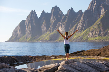 Young woman is practicing yoga between mountains in Norway