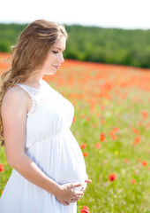 Fototapeta na wymiar Pregnant woman in poppy meadow 