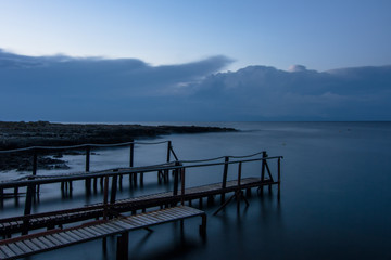 Fototapeta na wymiar Long exposure: a wooden pier after sunset in a blu autumn sky