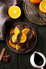Delicious slices of orange coated chocolate on black background