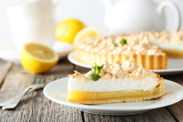 Lemon meringue pie on plate on grey wooden background