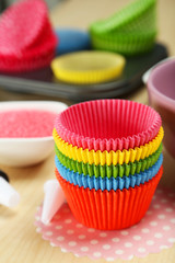 Empty colorful cupcake cases on wooden background