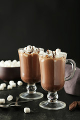 Glasses of hot chocolate with marshmallows on black background