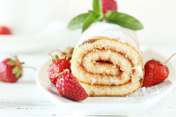 Fresh strawberries cake on plate on white wooden background