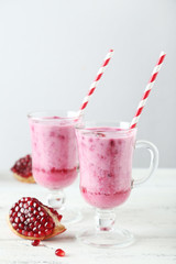 Pomegranate smoothie in glass on white wooden background
