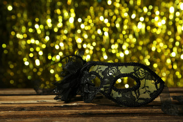 Female carnival mask with bokeh on brown wooden background