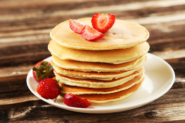 Delicious pancakes with strawberry on brown wooden background
