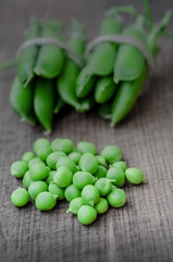 Green organic peas on wooden background, shalow focus