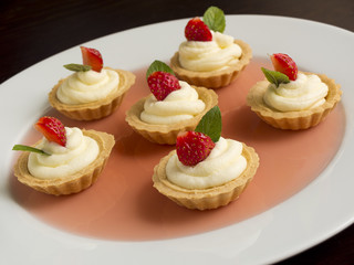 Tiny cupcakes with strawberry, whipped cream, jelly and mint