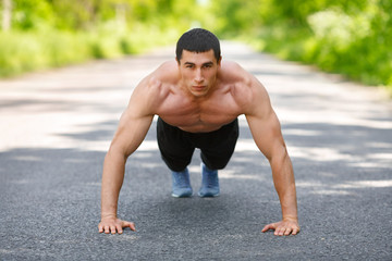 Fitness man exercising push ups, outdoor. Muscular male