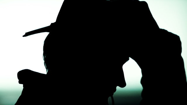 Black silhouette of man profile putting hat on