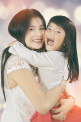Cheerful kid hugs her mother