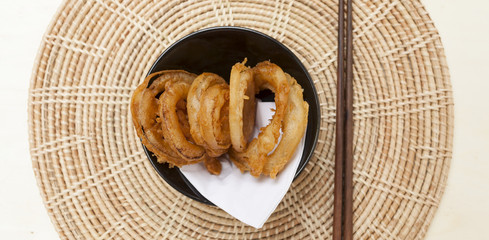 Golden onion ring on rattan placemat food banner style