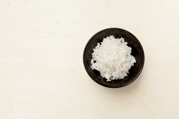 Rice in black bowl with space on wooden table background