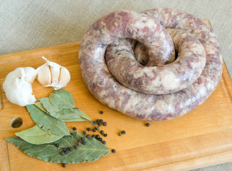 Uncooked homemade sausage on a gray sackcloth background
