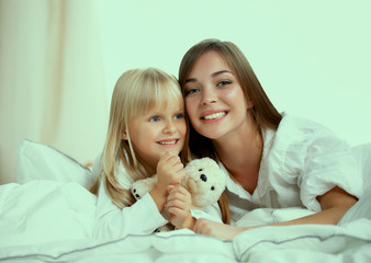 Woman and young girl lying in bed smiling