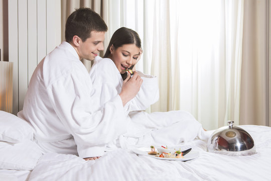 Young happy couple having breakfast in luxury hotel room.
