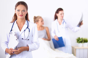 Fototapeta premium Smiling female doctor with a folder in uniform standing at