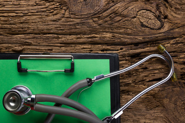 Workplace of a doctor. Medical clipboard and stethoscope on wooden desk background. Top view