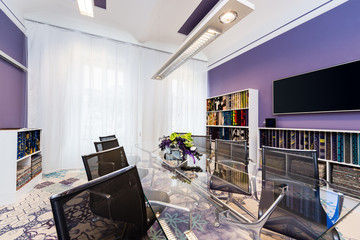 Boardroom with glass table and blue-violet walls