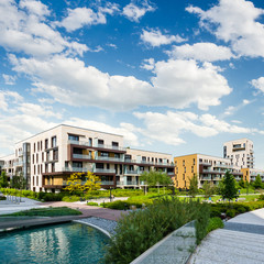 Public green park with modern blocks of flats and blue sk