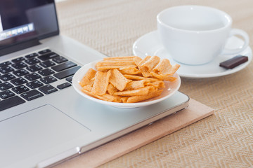 Laptop with coffee cup and snack