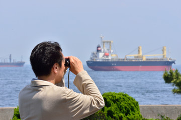 双眼鏡で海を眺める日本の男性