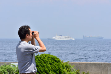 双眼鏡で海を眺める日本の男性