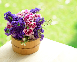 Bucket with wildflowers on the bench outdoors
