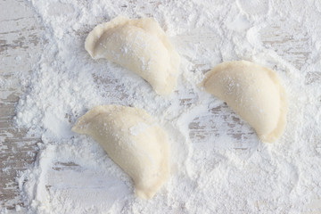 Homemade dumplings on wooden table with flour