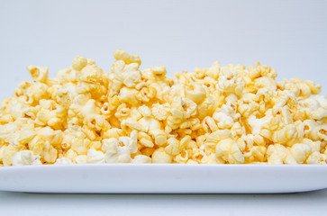 caramel popcorn grains on the white dish and white background