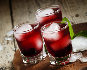 Red berry juice with ice in the shape of hearts, selective focus
