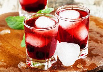 Red berry juice with ice in the shape of hearts, selective focus