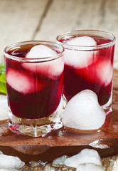 Red berry juice with ice in the shape of hearts, selective focus