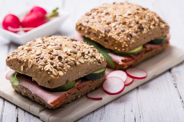 two sandwiches with ham, radishes and gherkin
