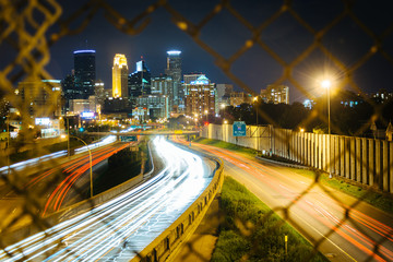 Chain link fence and view of I-35 and the skyline at night, seen