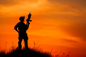 Fototapeta na wymiar Silhouette of military soldier or officer with weapons at sunset