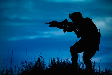 Silhouette of military soldier or officer with weapons at night.