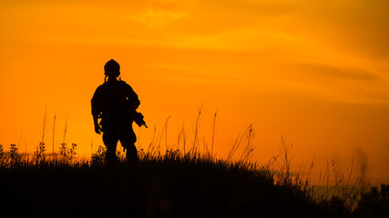 Silhouette of military soldier or officer with weapons at sunset