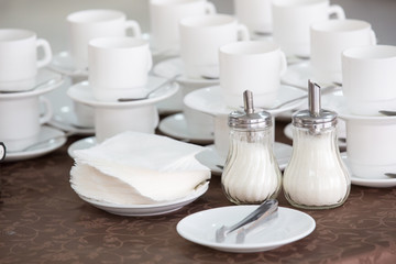 clean white cups and saucers, two sugar bowls and napkins