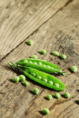 Opened green pea pods with peas in an old wooden table, selectiv