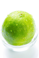 Green lime with water drops in the glass bowl