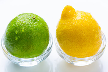 Lemon and green lime with water drops in the glass bowls