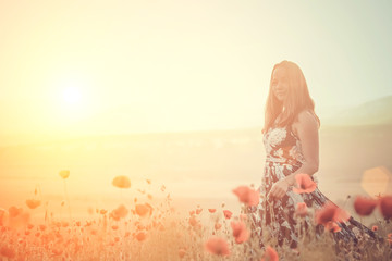 beautiful girl in a poppy field at sunset