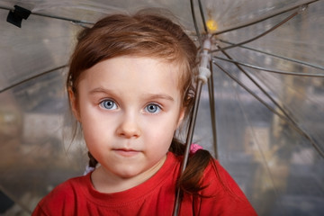 Portrait of little cute girl in red T-shirt holding an umbrella