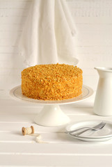 honey cake on a stand on a light wooden surface