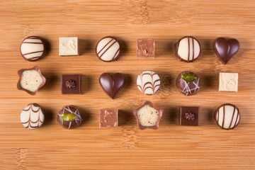 Assorted chocolate candies arranged in rows on a wooden surface