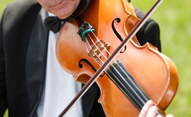 Fototapeta premium Musician with bow tie plays violin outdoors