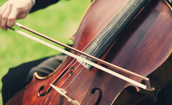Man's hands playing violoncello outdoors